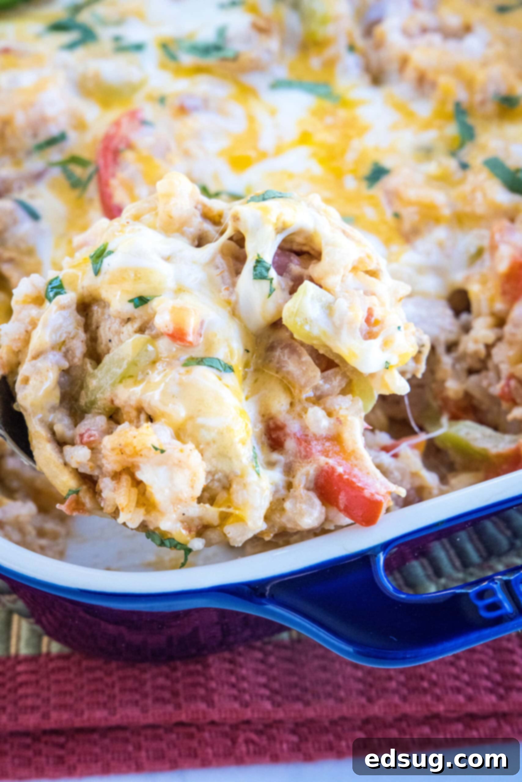 This chicken fajita casserole is an easy dinner packed with juicy chicken and rice, with sweet bell peppers, fajita seasoning, and cheese! A serving of chicken fajita casserole being scooped from a baking dish, showcasing the melty cheese and tender chicken.