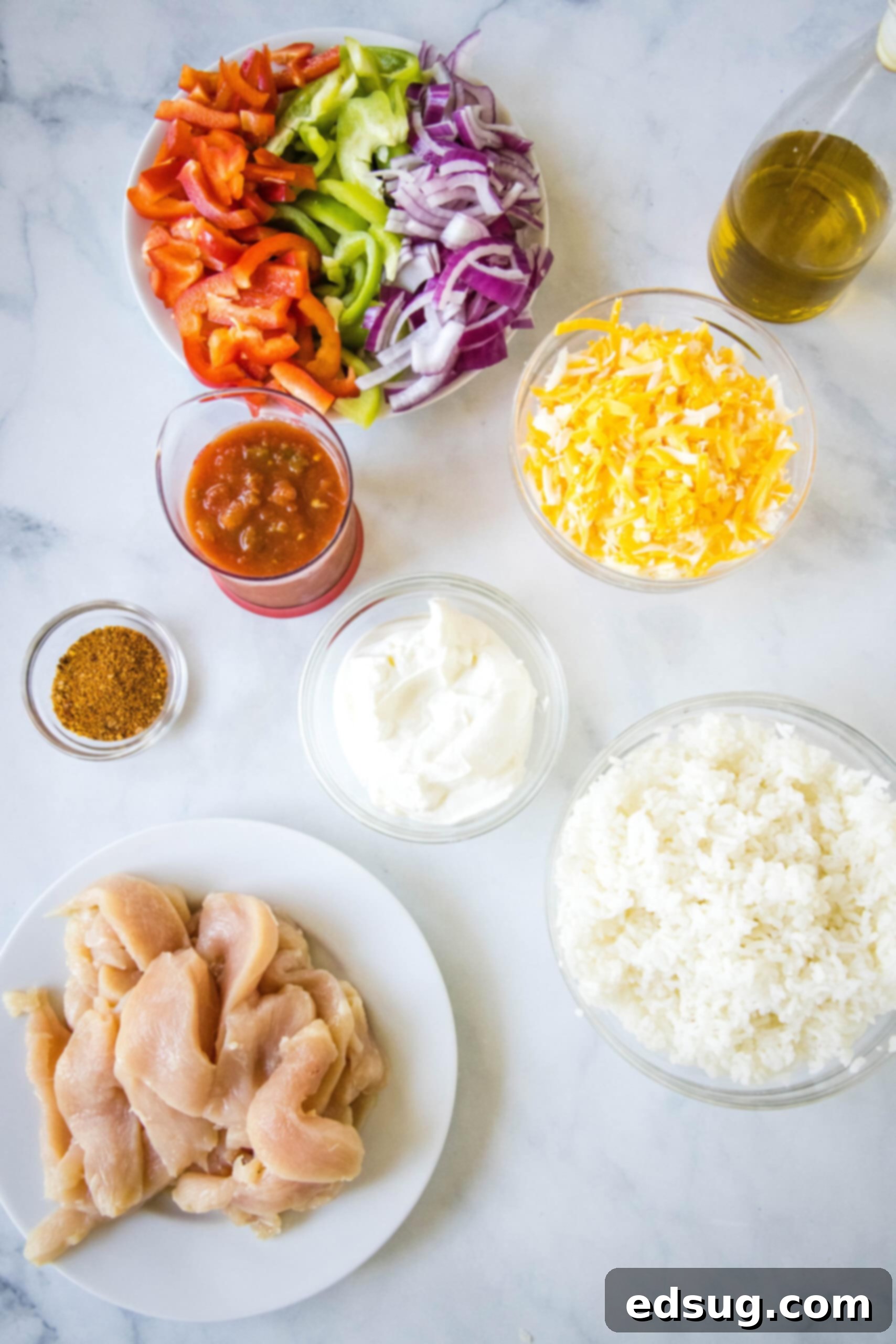 This chicken fajita casserole is an easy dinner packed with juicy chicken and rice, with sweet bell peppers, fajita seasoning, and cheese! Various ingredients for chicken fajita casserole laid out on a kitchen counter, including sliced chicken, bell peppers, onions, rice, cheese, salsa, and sour cream.
