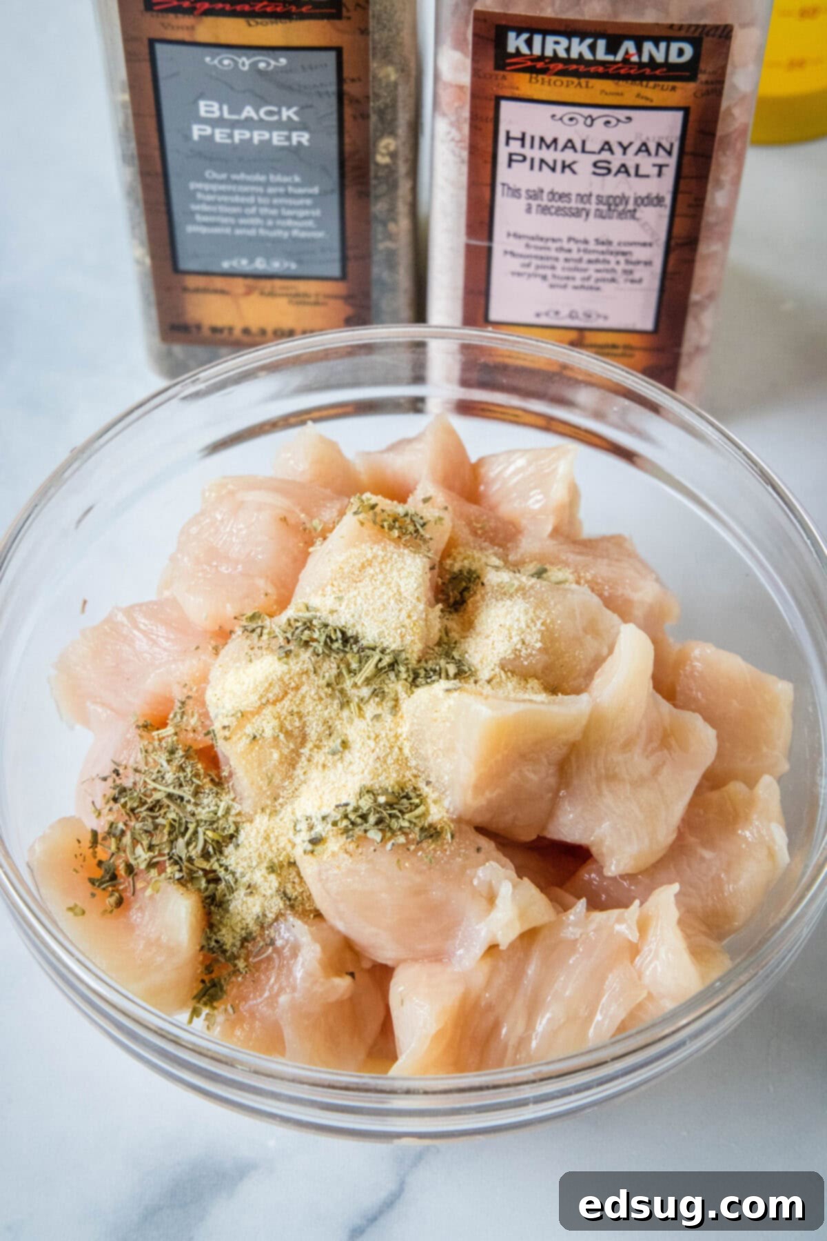 Flavor-packed Marry Me Chicken pasta is a 30-minute, one-pan weeknight dinner with tender pasta and chicken in creamy sun-dried tomato sauce. Seasonings added to cubed chicken in a glass bowl.