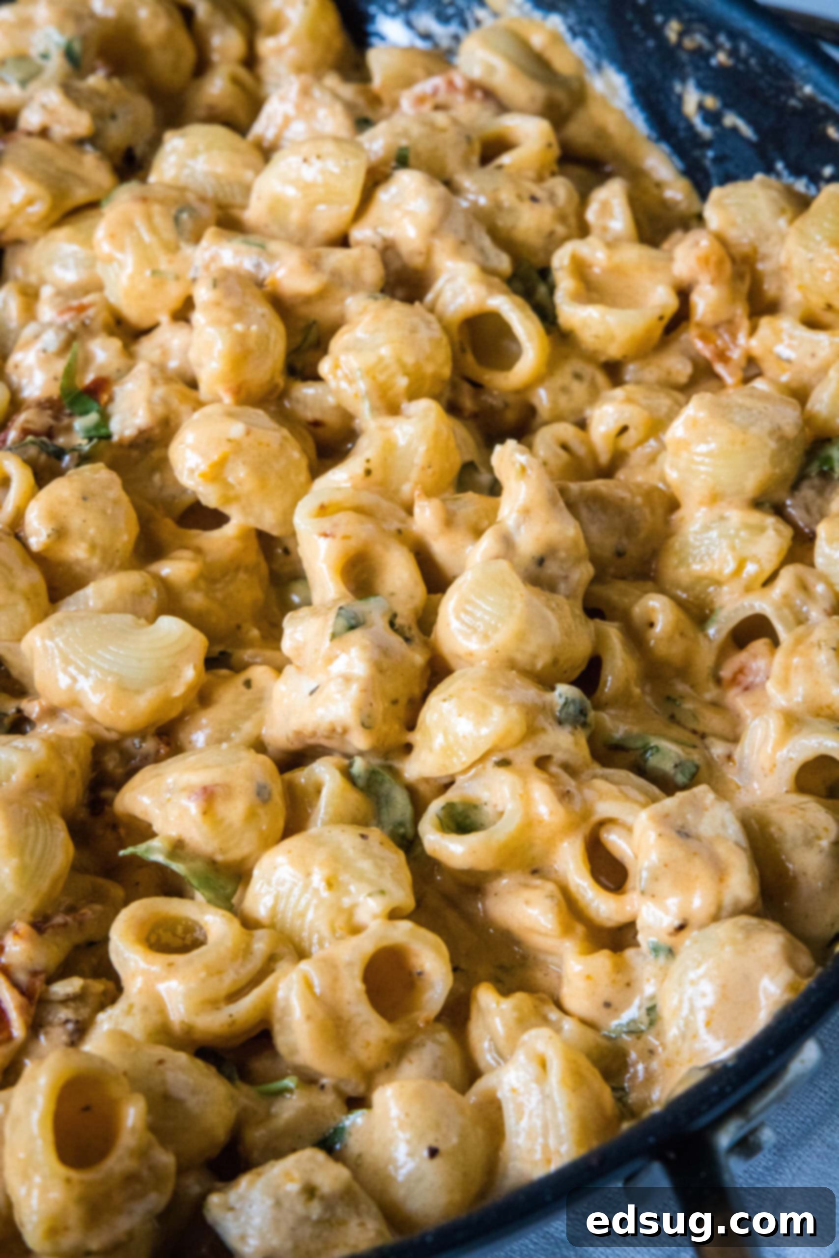 Proposal Worthy Chicken Pasta 2 Close up of a spoon stirring Marry Me Chicken pasta in a skillet.