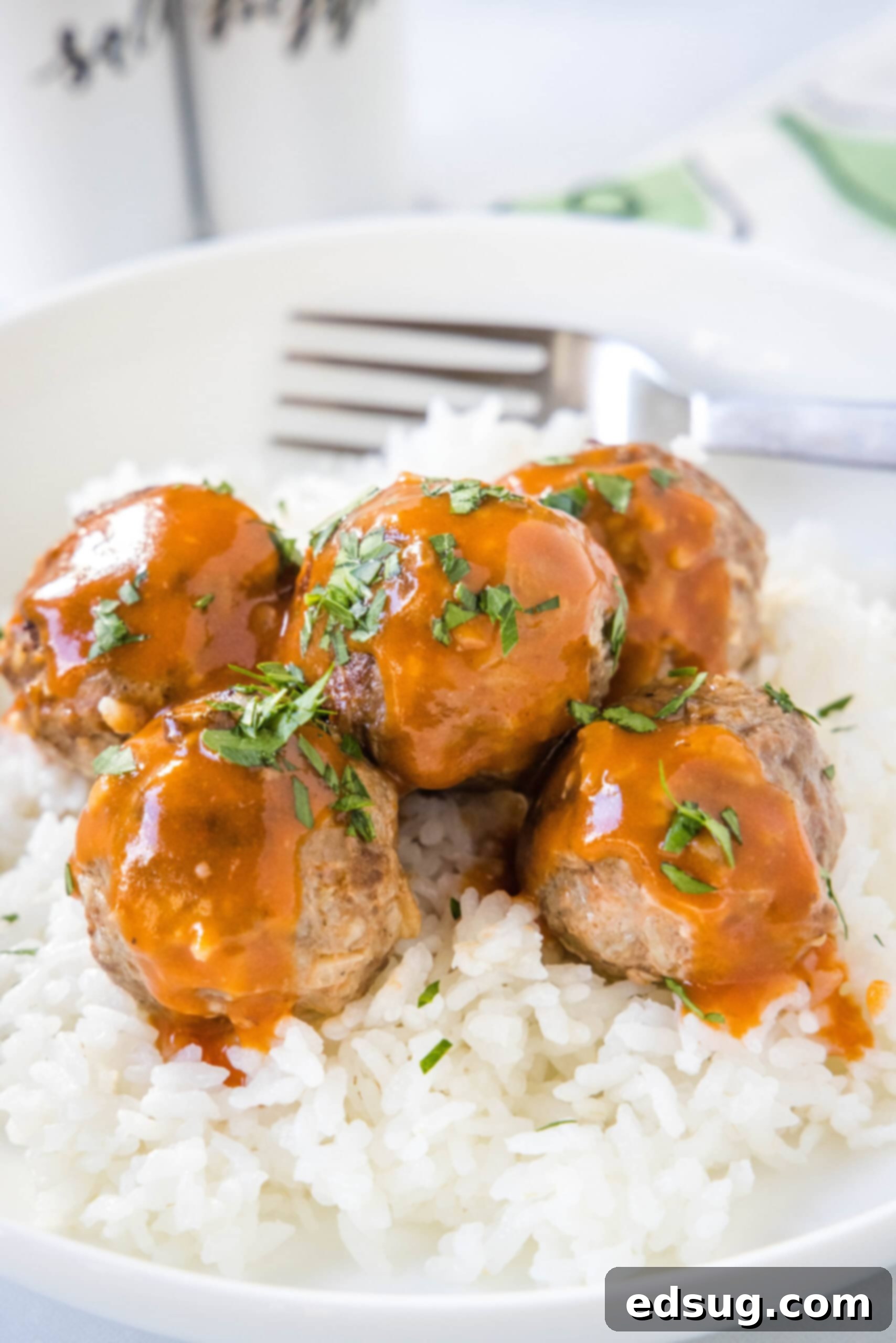 Porcupine meatballs served over a bed of white rice in a bowl with a fork.