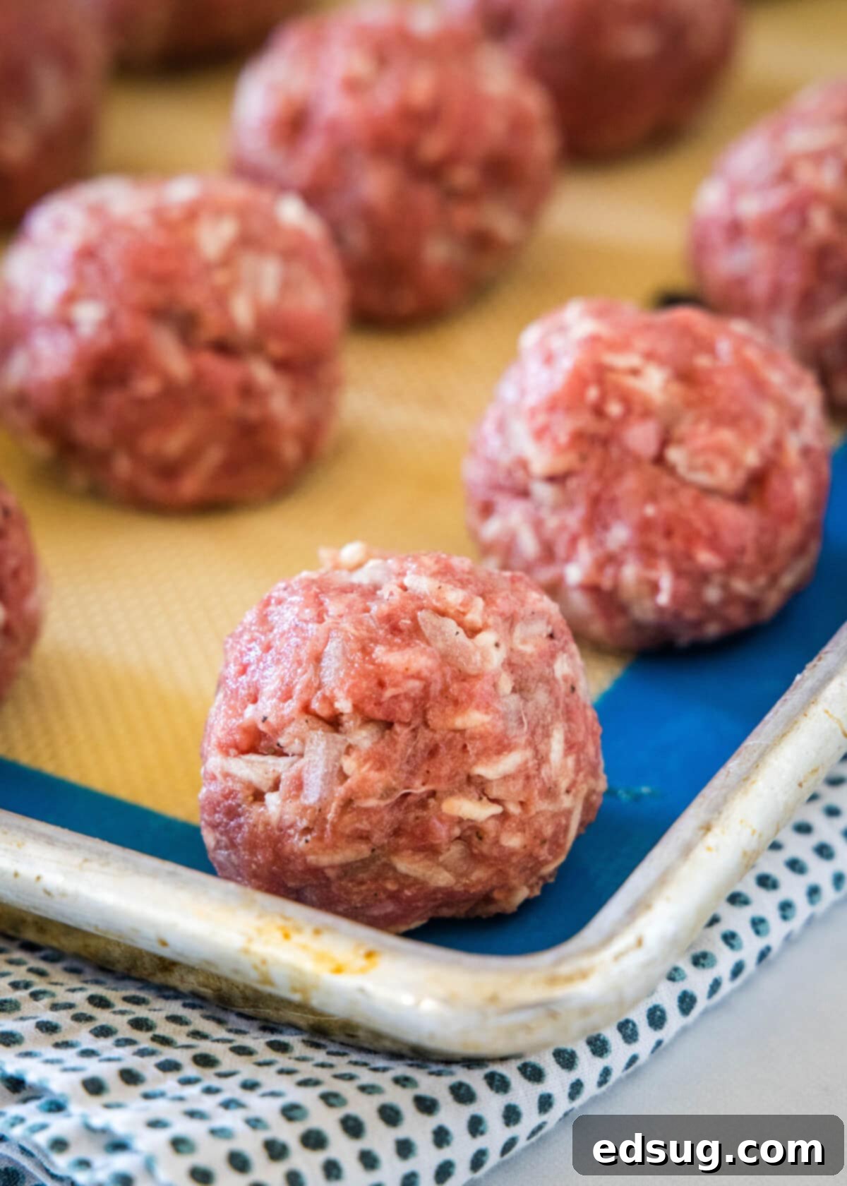 Rows of unbaked porcupine meatballs on a lined baking sheet.