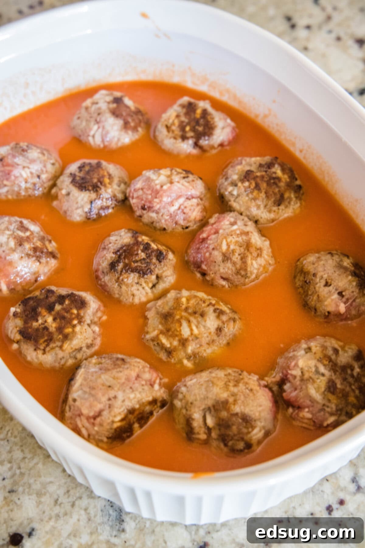 Porcupine meatballs added to a casserole dish with tomato soup.