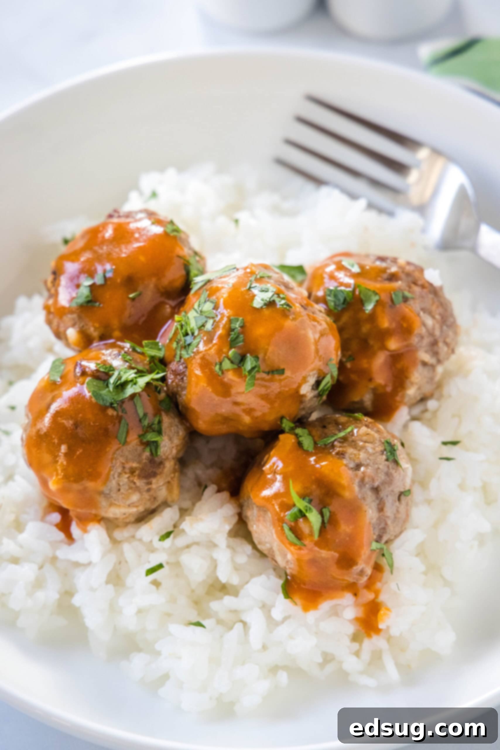 Porcupine meatballs served over a bed of white rice in a bowl with a fork.