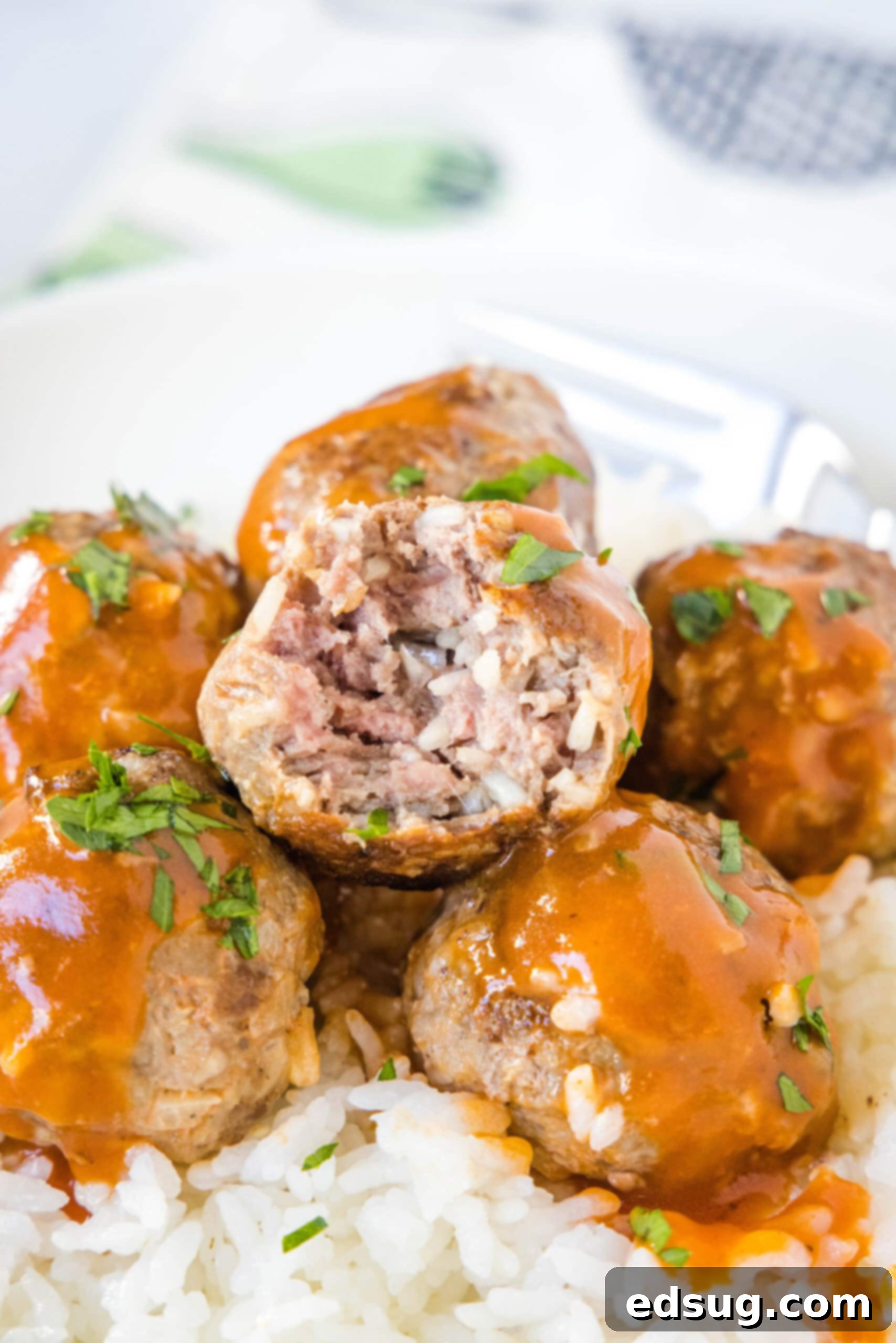 Porcupine meatballs served over a bed of white rice, with a bite missing from the top meatball.