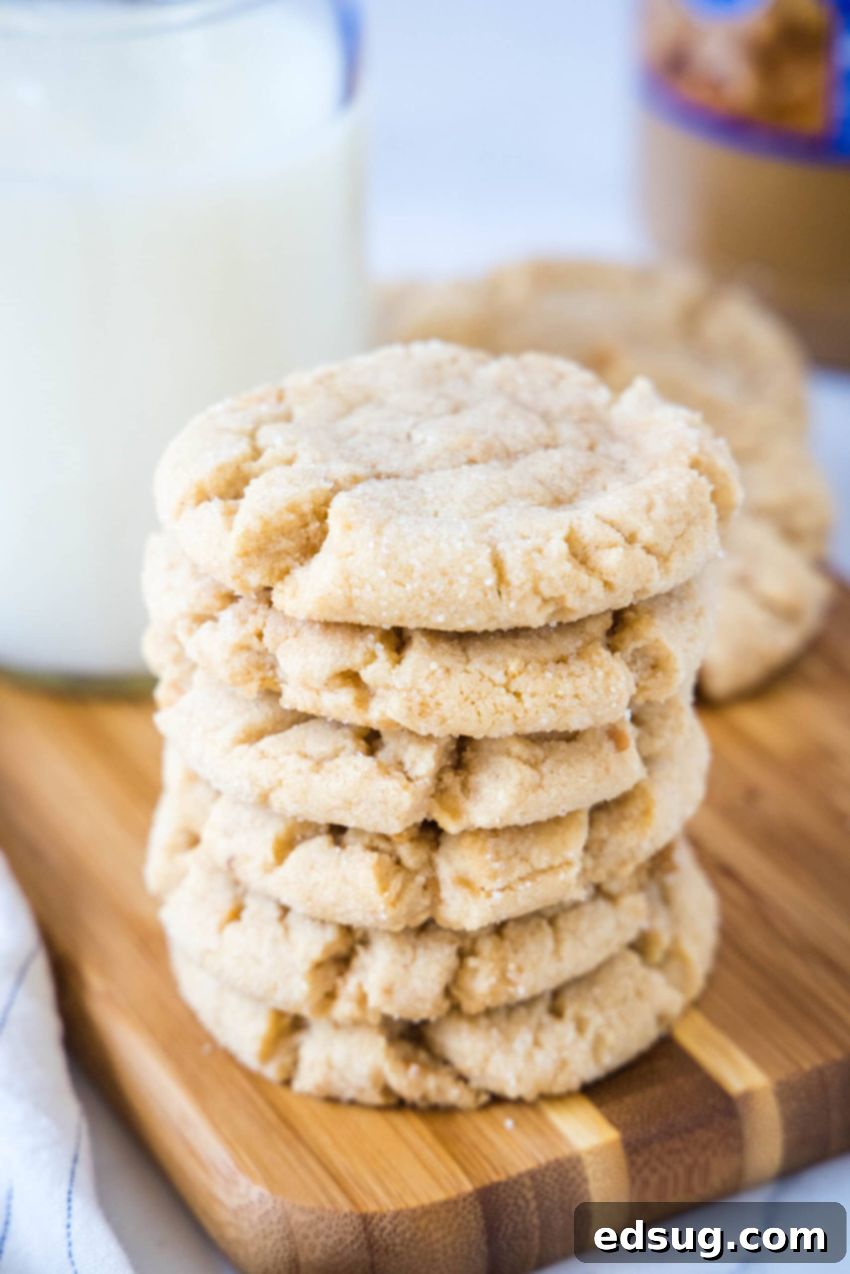 A beautifully arranged stack of golden brown, textured crunchy peanut butter cookies on a rustic wooden cutting board, ready to be enjoyed.