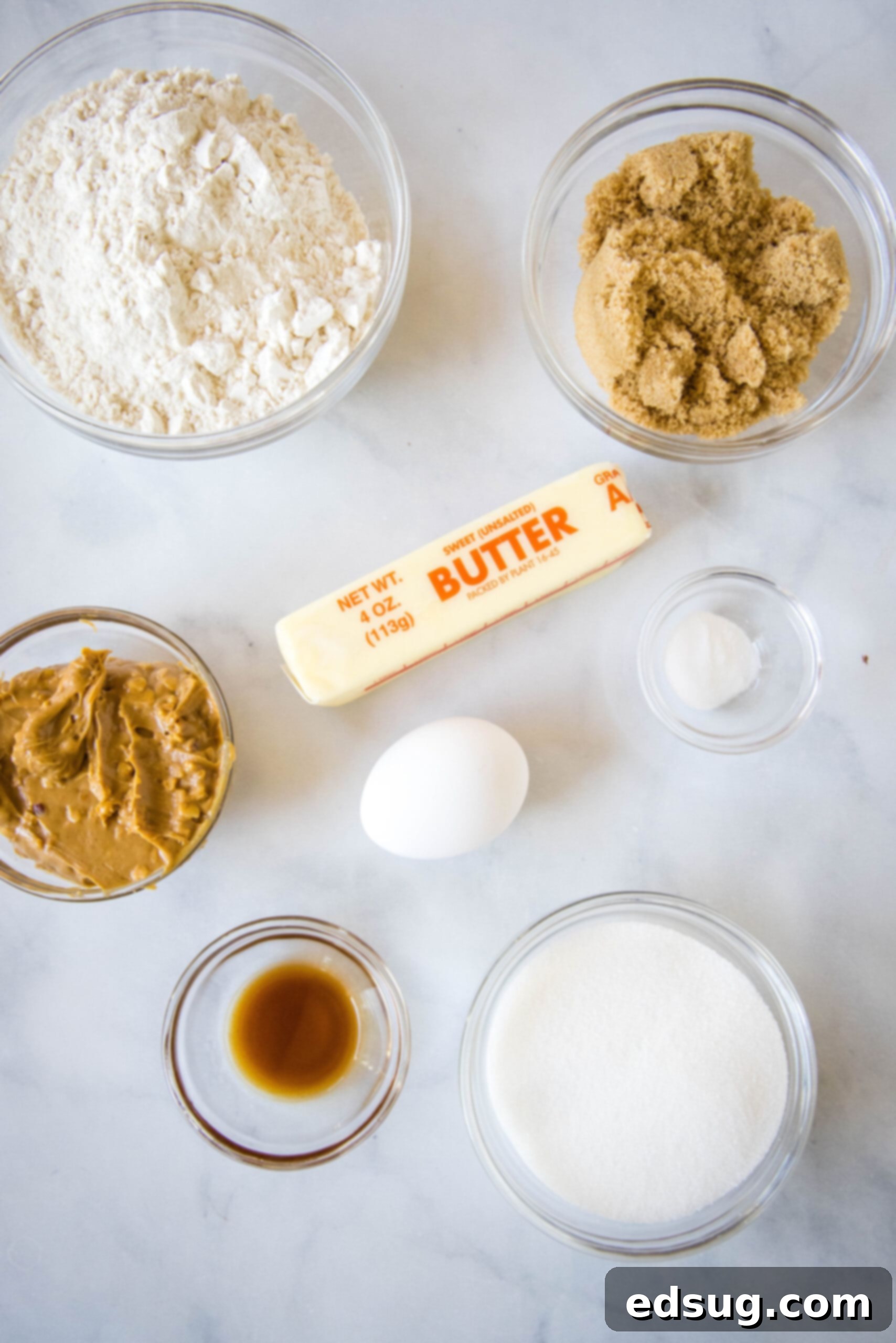 A colorful array of ingredients for crunchy peanut butter cookies, including butter, sugars, peanut butter, and flour, laid out for preparation.
