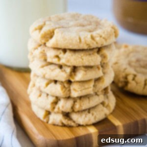 A stack of crunchy peanut butter cookies on a wooden cutting board.