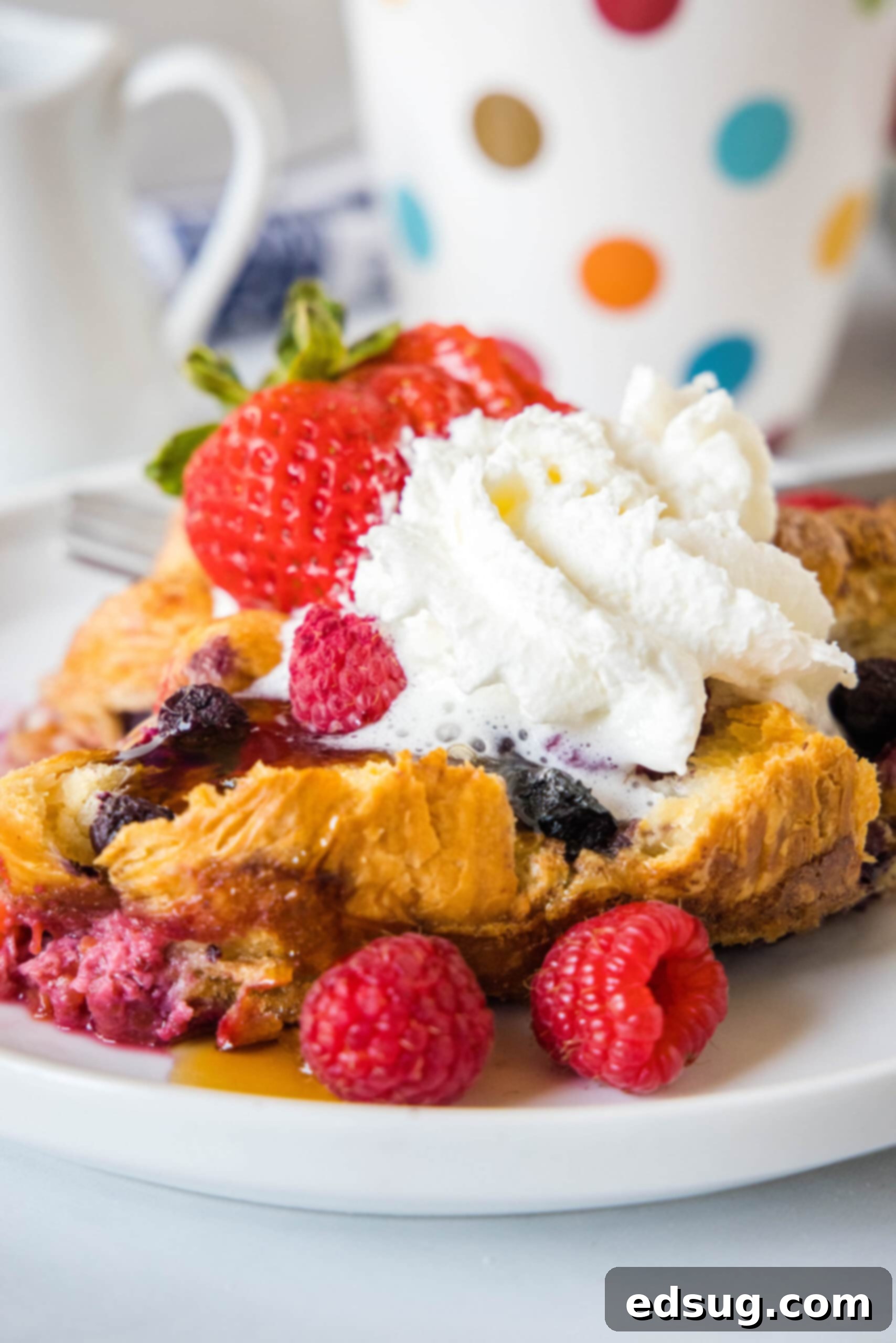 This overnight croissant baked French toast has buttery croissants layered in a rich, spiced custard with berries. It's prepped in minutes! A serving of croissant baked French toast topped with maple syrup, whipped cream, and fresh berries on a plate. This easy overnight breakfast casserole is perfect for holidays.