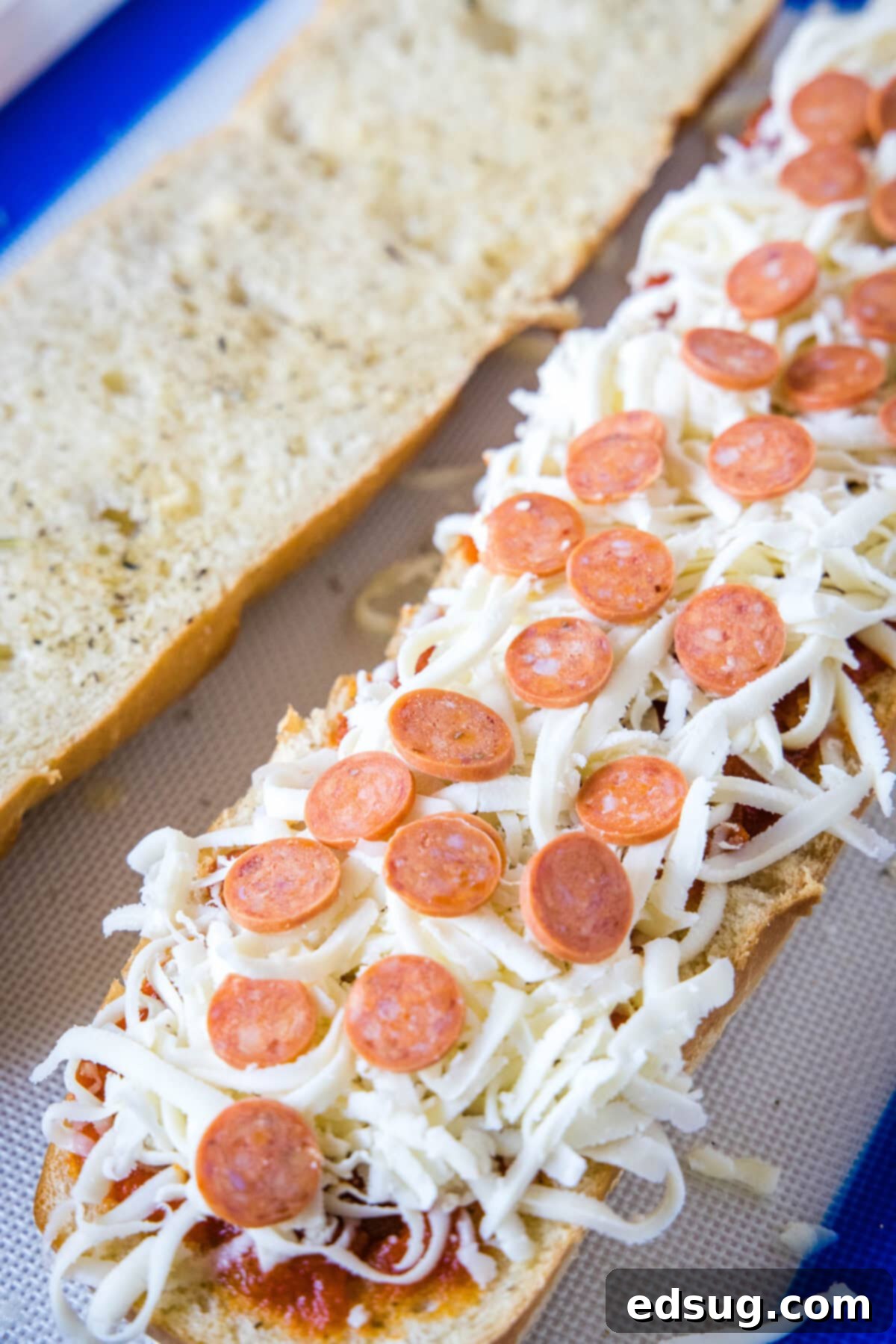Quickly assemble your French bread pizzas by adding your favorite toppings over the sauce and cheese, then bake to perfection! Partially assembled French bread pizzas on a baking sheet, topped with sauce, cheese, and pepperoni.