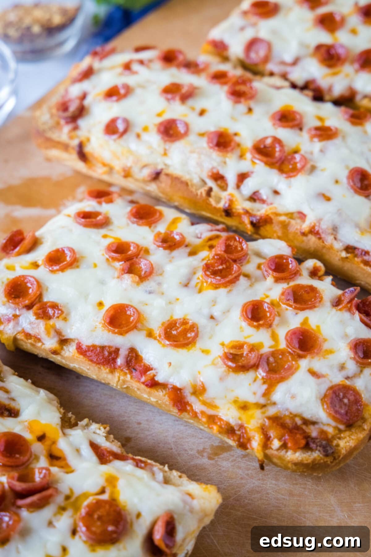 A feast of easy French bread pizzas, straight from the oven, featuring zesty garlic butter, savory pizza sauce, melty mozzarella, and your preferred toppings! Several French bread pizzas, freshly baked and golden, arranged artfully on a wooden cutting board.