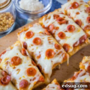 Crispy French Bread Pizzas 2 Delicious French bread pizza cut into slices on a wooden cutting board, garnished with fresh herbs.