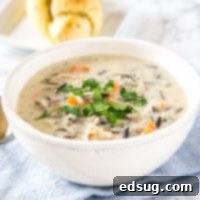 A bowl of creamy wild rice soup with a spoon.