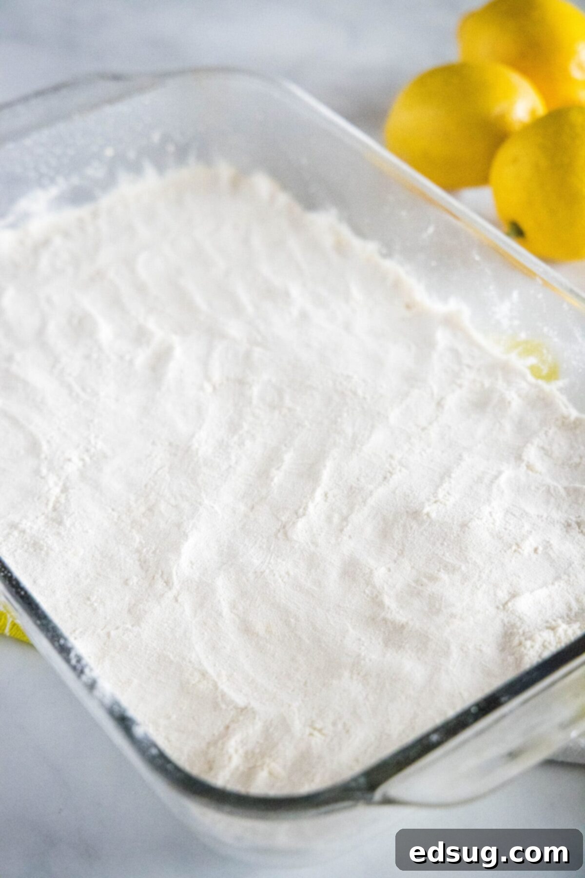 A 13x9-inch baking pan filled with uncooked lemon bar shortbread dough, pressed evenly into the bottom