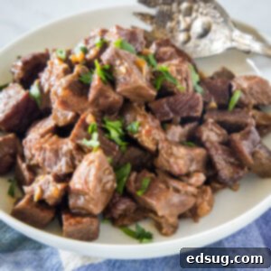 Slow cooker steak bites in a serving bowl with a large fork.