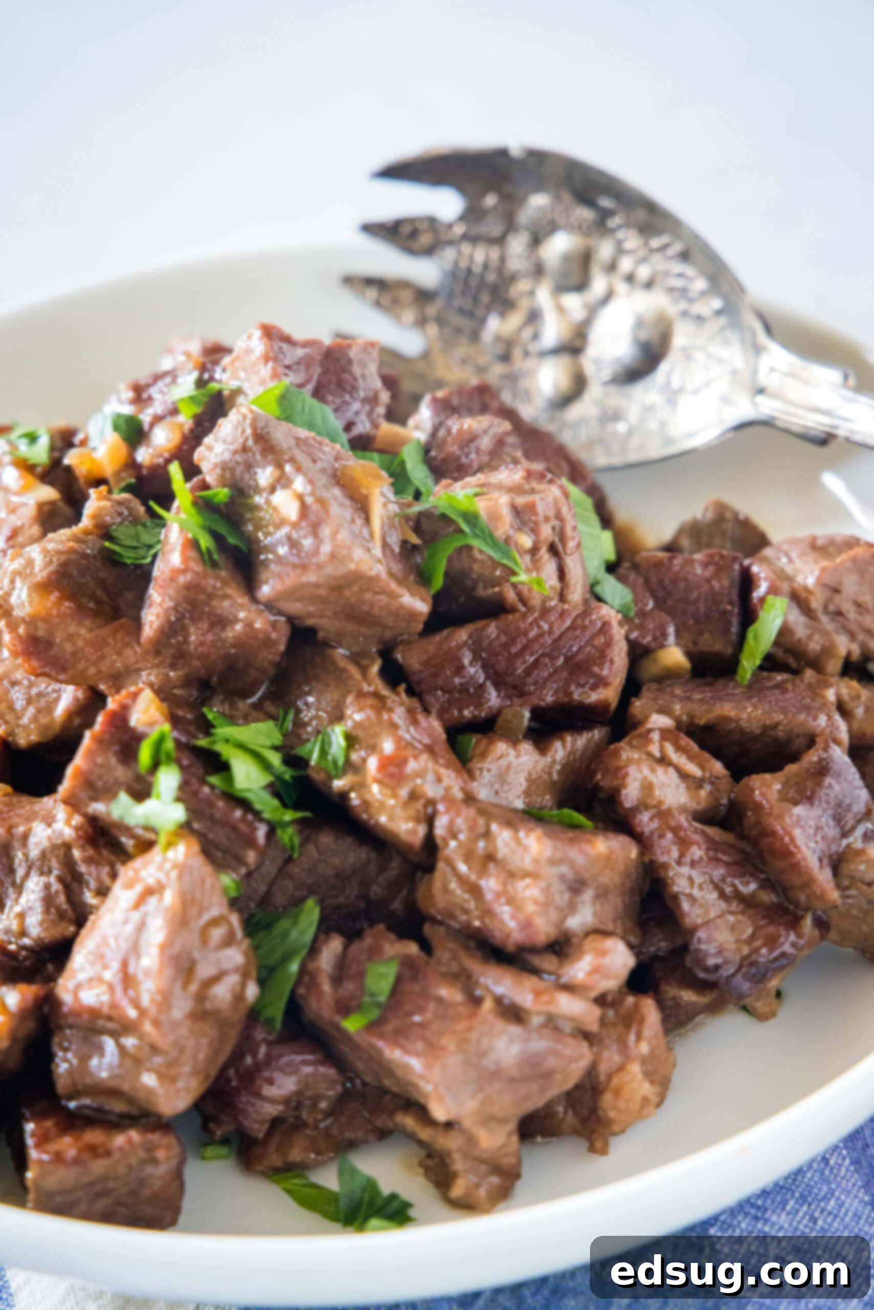 Slow cooker steak bites in a serving bowl with a large fork.