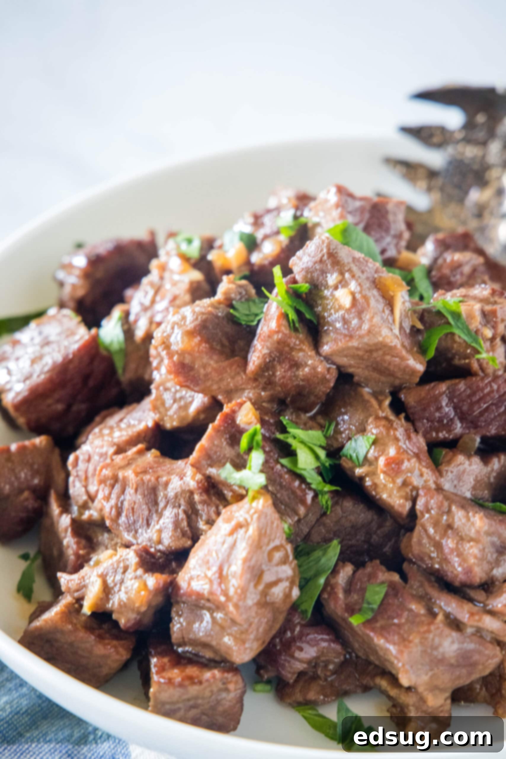 Slow cooker steak bites in a serving bowl with a large fork.