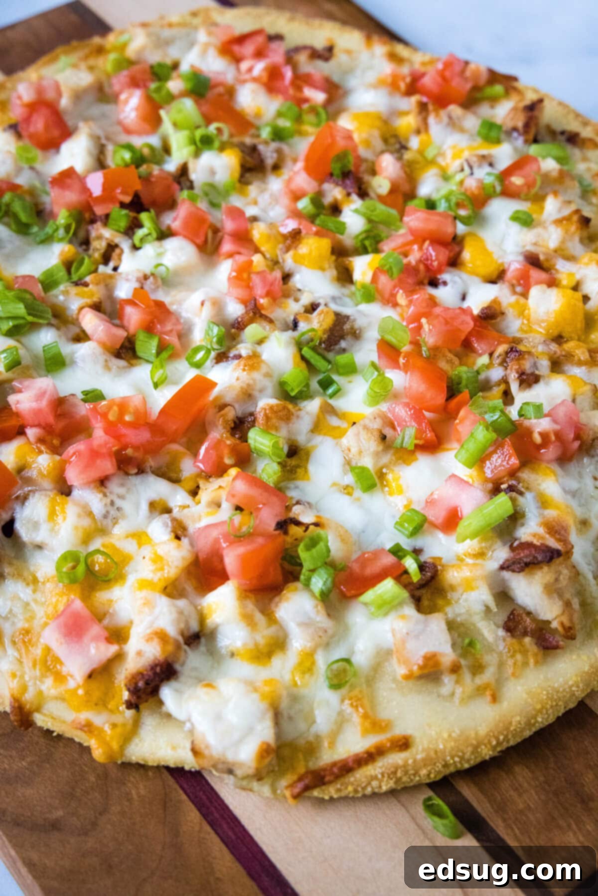 chicken bacon ranch pizza topped with tomatoes and green onions