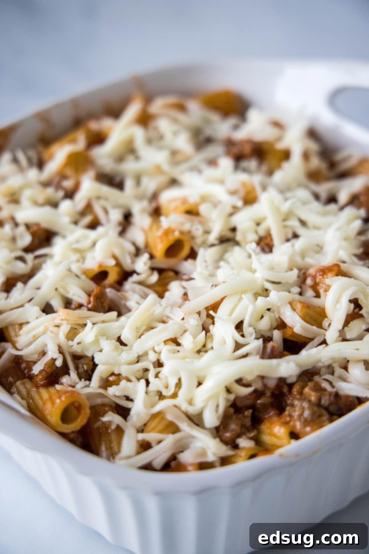 Hearty Italian Sausage Bake 4 sausage casserole ready for the oven topped with shredded cheese