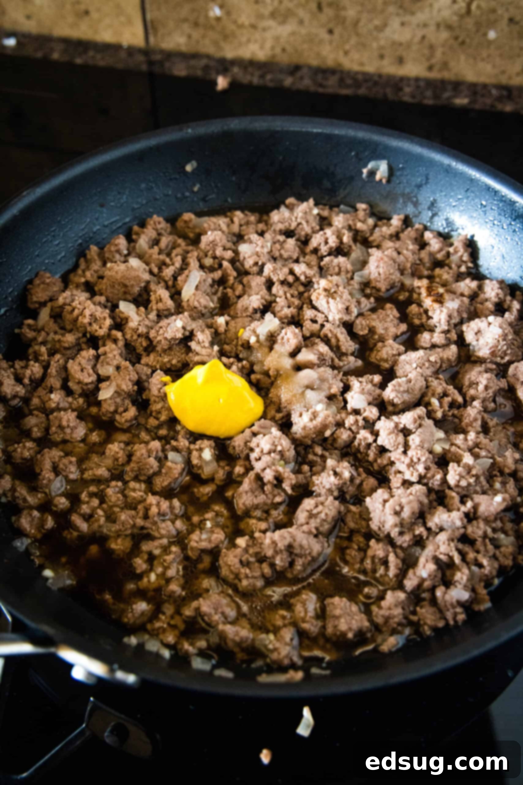 Adding mustard and seasonings to the browned ground beef in a skillet for a flavorful Maid-Rite filling. Mustard and seasonings added to browned ground beef in a skillet.