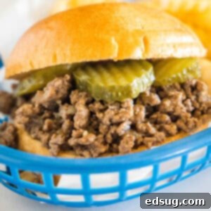 True Traditions 2 Close up of a Maid Rite loose meat sandwich garnished with pickles in a blue plastic serving basket.