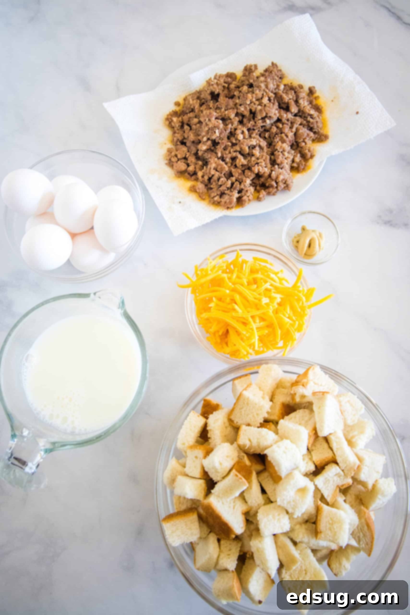 This sourdough breakfast casserole is the ultimate make-ahead breakfast packed with sourdough bread chunks, breakfast sausage, and cheese! All the fresh ingredients for a sourdough breakfast casserole laid out, including sourdough bread, breakfast sausage, cheese, eggs, milk, and Dijon mustard.