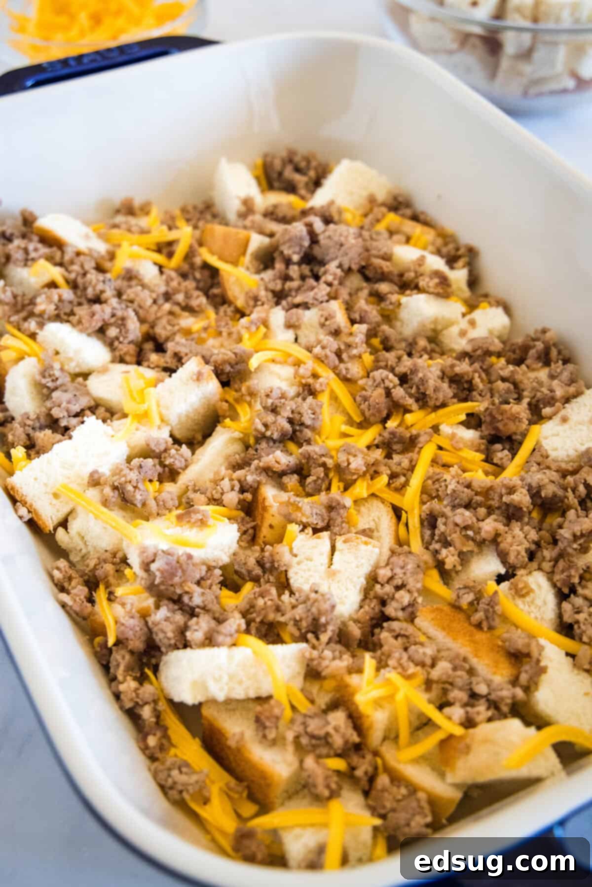 This sourdough breakfast casserole is the ultimate make-ahead breakfast packed with sourdough bread chunks, breakfast sausage, and cheese! Layering sourdough bread cubes, cooked sausage, and shredded cheese in a greased baking dish for a breakfast casserole.