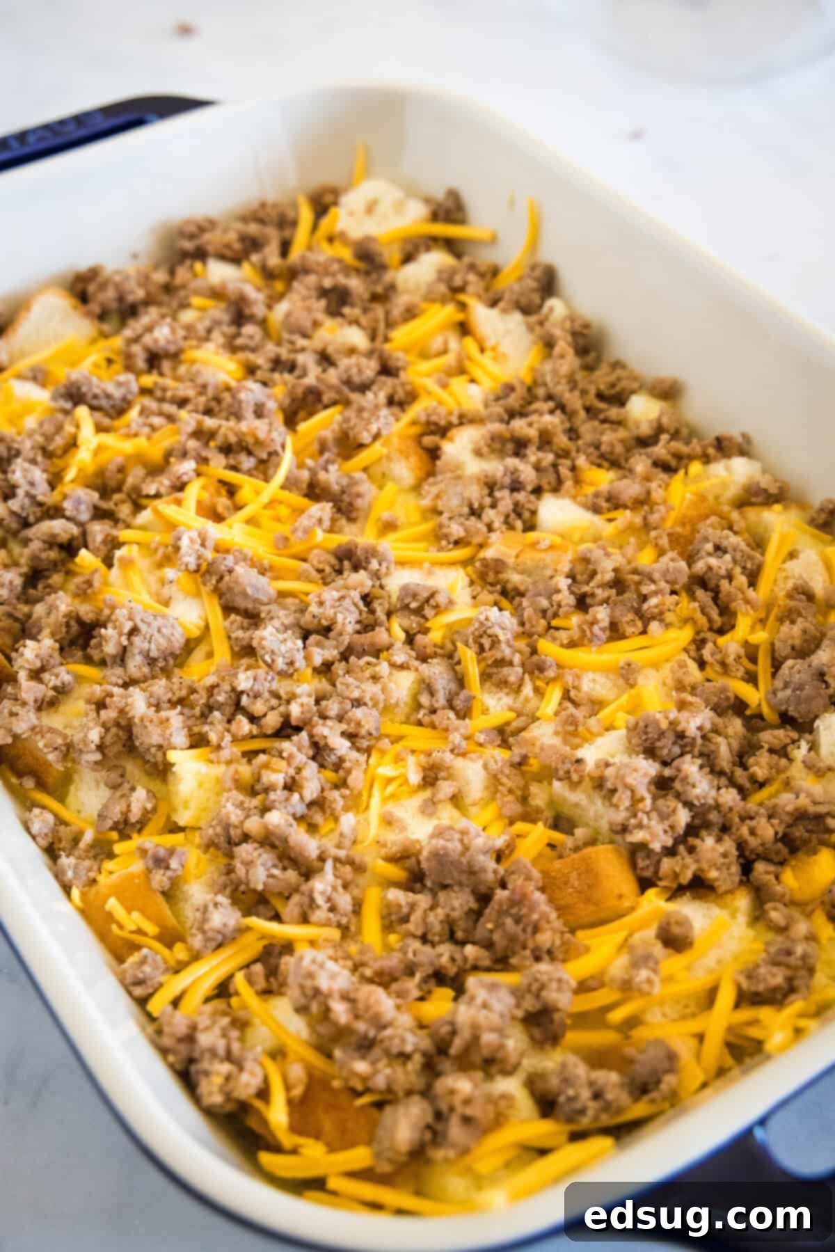 This sourdough breakfast casserole is the ultimate make-ahead breakfast packed with sourdough bread chunks, breakfast sausage, and cheese! The assembled sourdough breakfast casserole covered with plastic wrap, ready for refrigeration overnight.