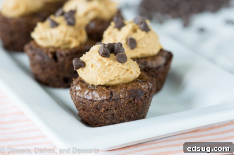 A top-down view of Peanut Butter Brownie Bites in a mini muffin tin, with a few removed showing the peanut butter filling