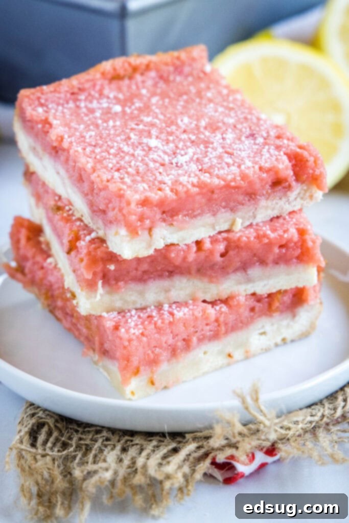 Bright & Tangy Strawberry Lemonade Treats 6 Several neatly cut strawberry lemon bars, stacked artfully to show their distinct layers, dusted with powdered sugar.