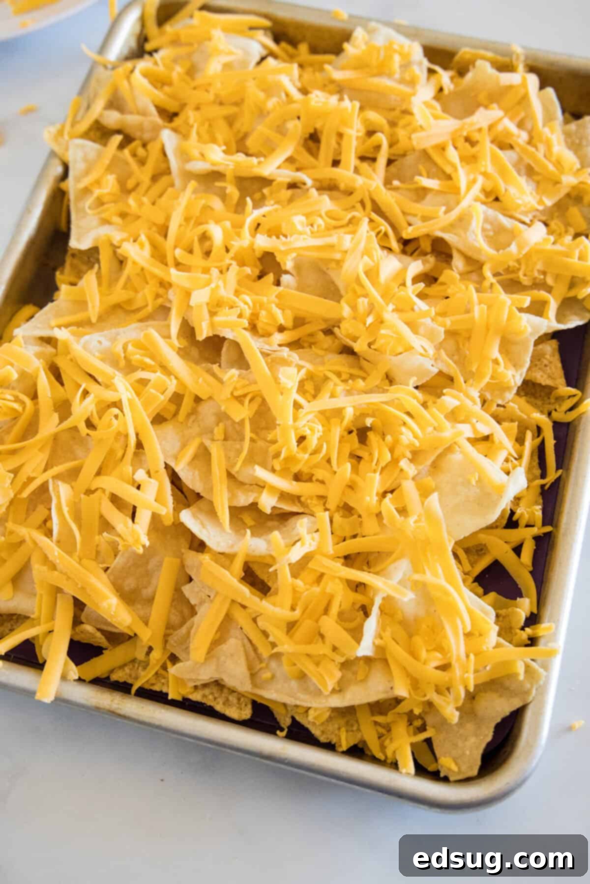 Upgrade classic nachos with zesty seasoned shrimp! These shrimp nachos are an easy Tex-Mex appetizer packed with flavor, ready in 15 minutes. Assembled shrimp nachos topped with shredded cheese.
