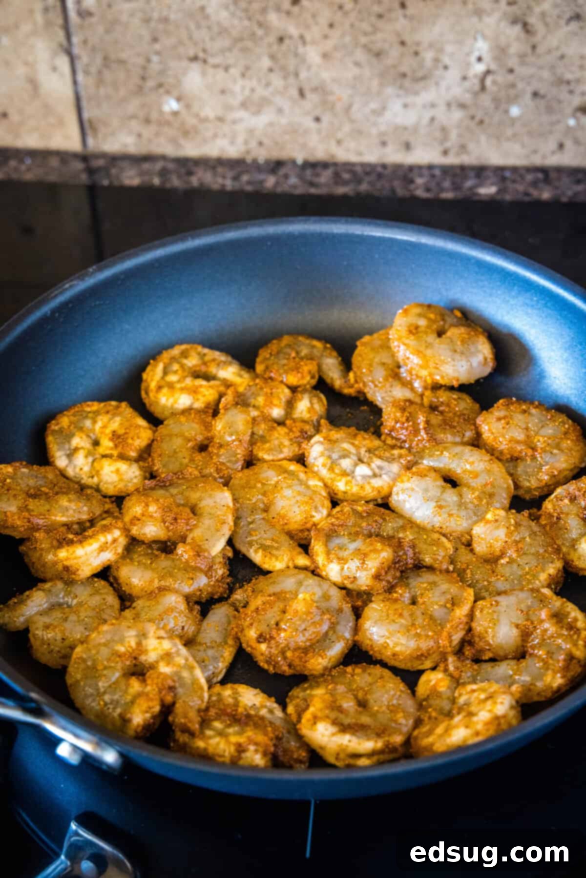 Upgrade classic nachos with zesty seasoned shrimp! These shrimp nachos are an easy Tex-Mex appetizer packed with flavor, ready in 15 minutes. Seasoned shrimp cooking in a skillet.