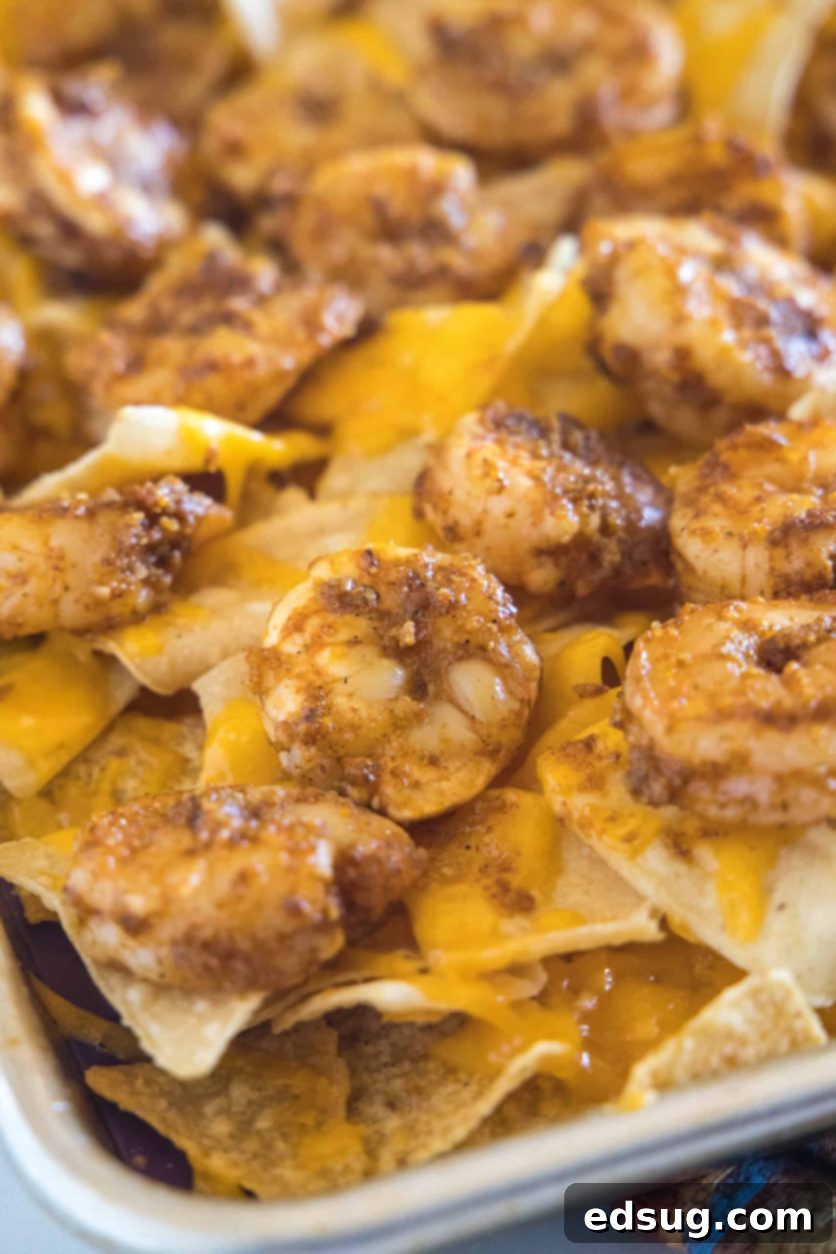 Upgrade classic nachos with zesty seasoned shrimp! These shrimp nachos are an easy Tex-Mex appetizer packed with flavor, ready in 15 minutes. Tortilla chips baked with shredded cheese and seasoned shrimp on a sheet pan.