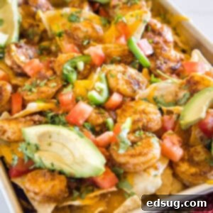Baja Shrimp Nachos 2 Shrimp nachos on a sheet pan garnished with avocado slices.