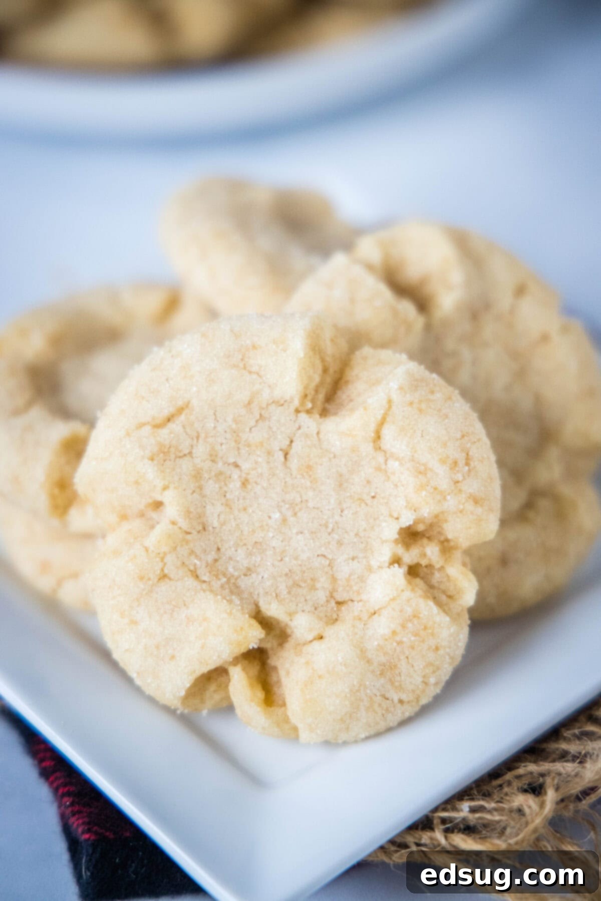 Several perfectly golden brown Angel Crisp cookies are elegantly arranged on a white plate, highlighting their distinctive texture, sugar coating, and inviting homemade appeal.