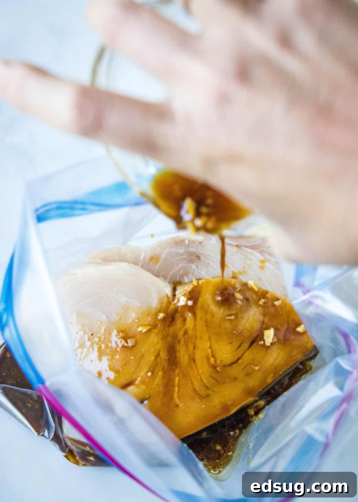 Pouring swordfish marinade into a resealable plastic bag with swordfish steaks