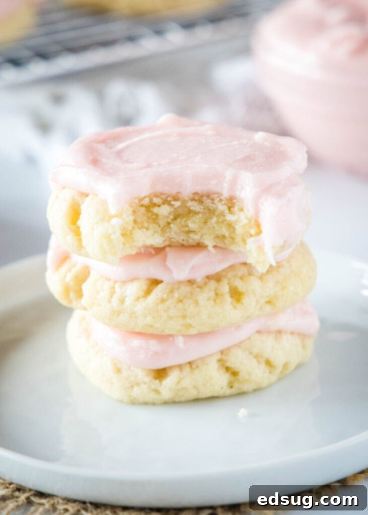 The Quintessential Sugar Cookie 2 A stack of thick, frosted bakery style sugar cookies on a white plate, ready to be enjoyed.