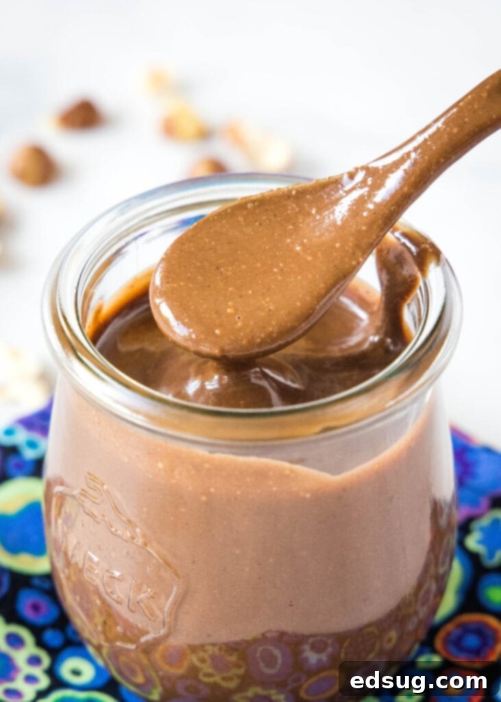 Homemade Chocolate Hazelnut Spread 2 a jar of homemade nutella with a spoon in it, showcasing its rich, creamy texture