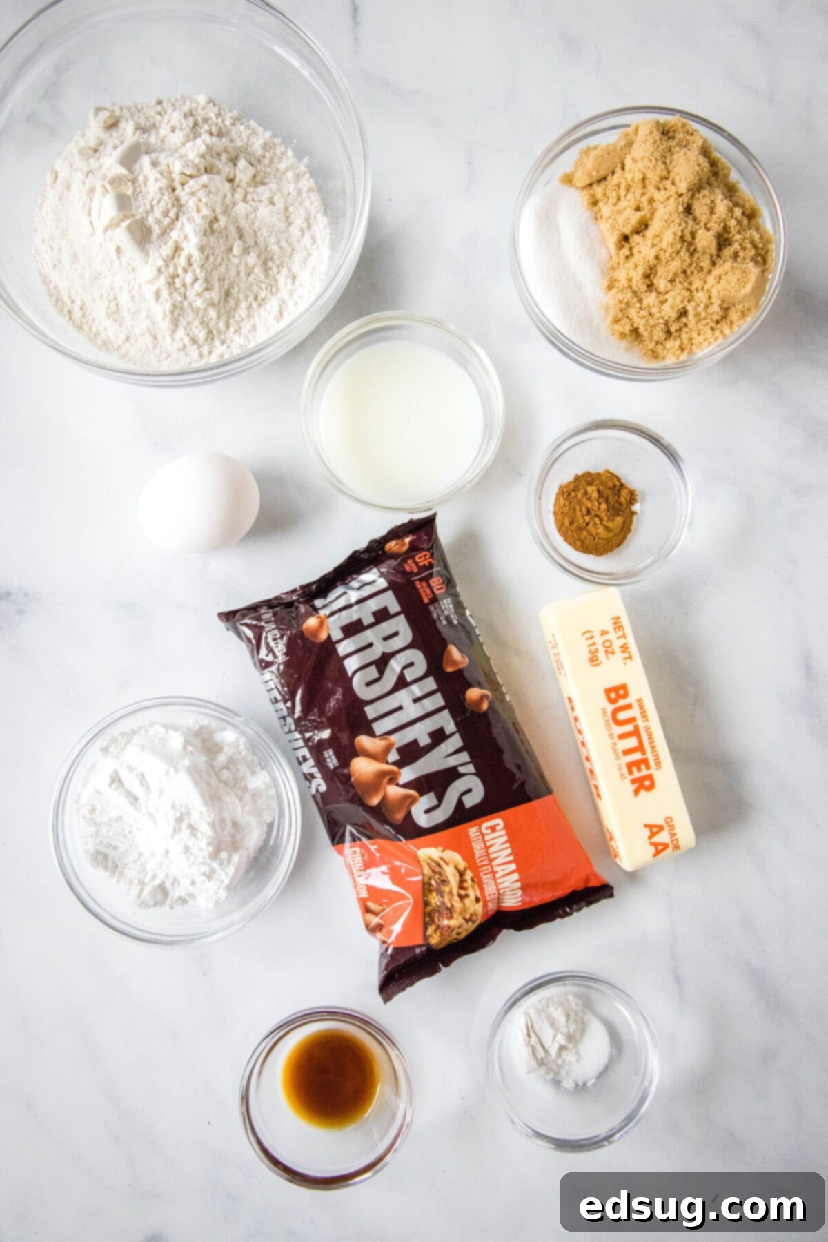 Cozy Cinnamon Blondies 3 Close-up of the essential ingredients for cinnamon blondies, including butter, sugars, flour, and cinnamon chips arranged on a white surface.
