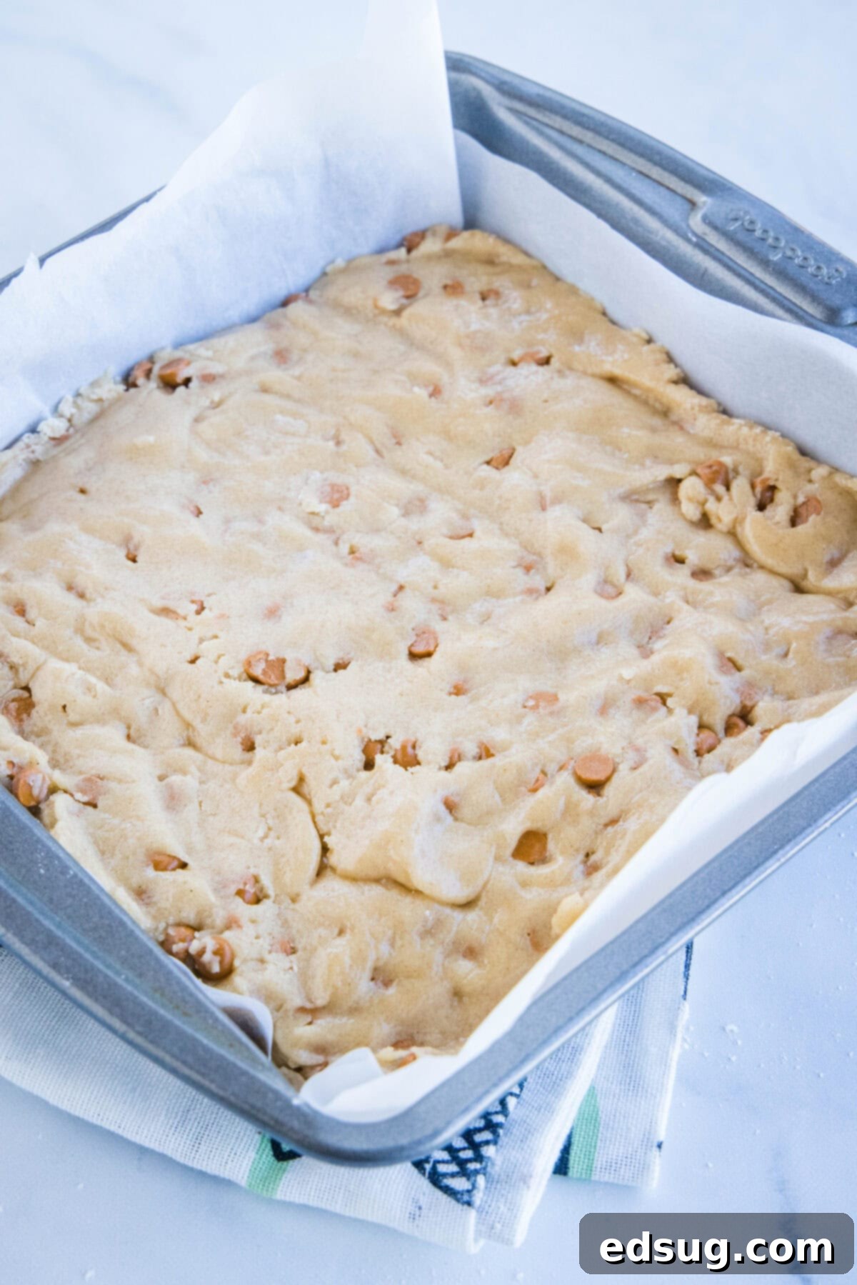 Cozy Cinnamon Blondies 4 Cinnamon blondie batter evenly spread in an 8-inch baking pan, ready to be placed in the oven for baking.