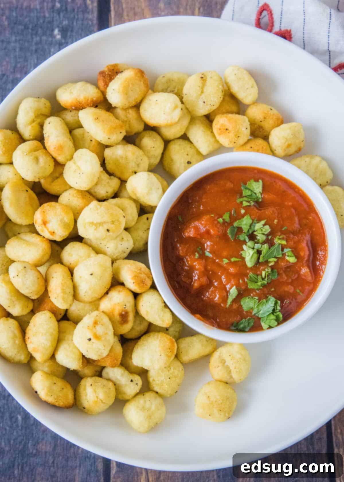 Air Fryer Gnocchi 2 crispy gnocchi on a plate with bowl of marinara sauce