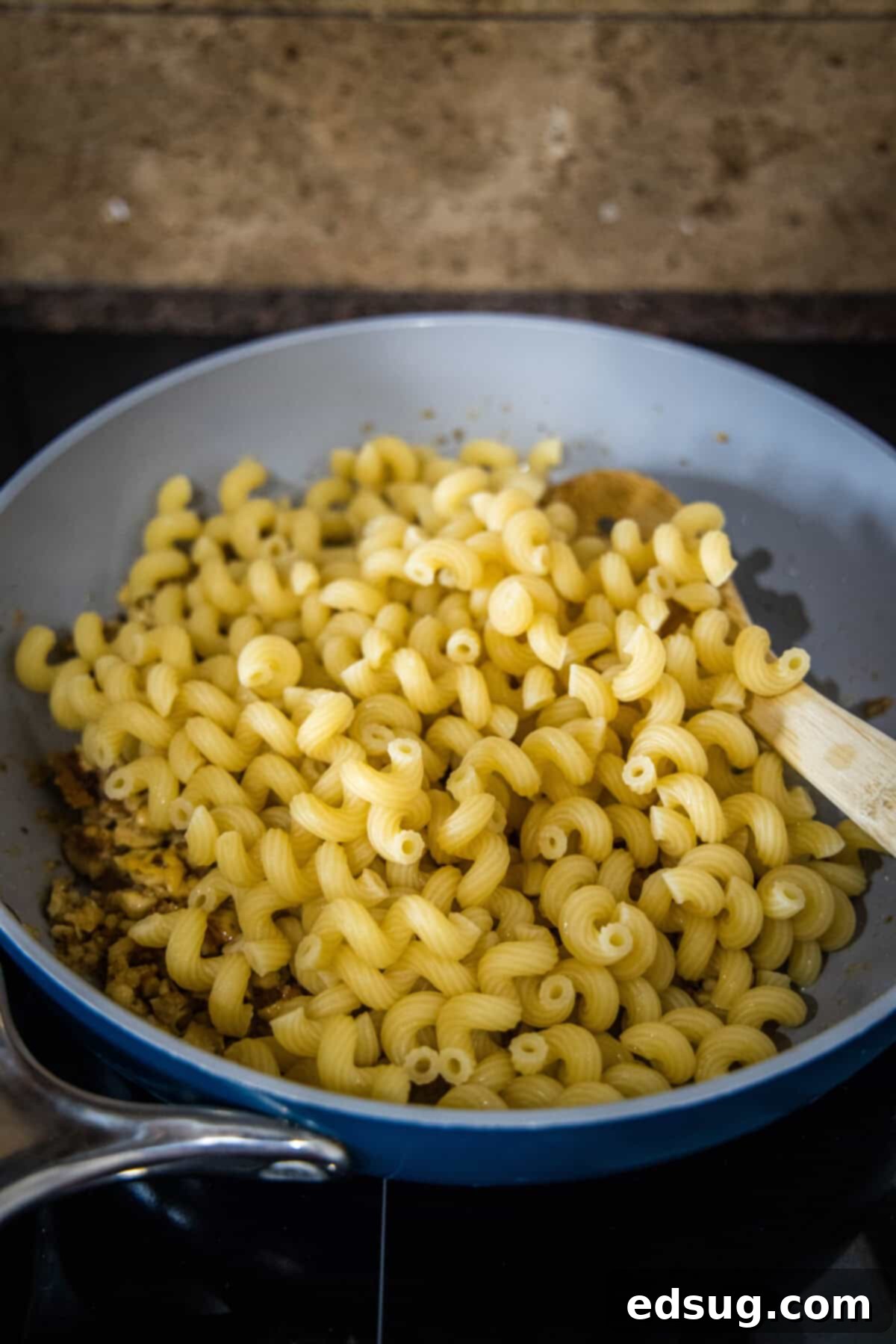 This toasted walnut pasta is an easy, flavorful, and filling 15-minute pasta recipe with crunchy walnuts, breadcrumbs, garlic, and chili. Drained cooked pasta being added to the skillet with the toasted walnut and breadcrumb sauce.