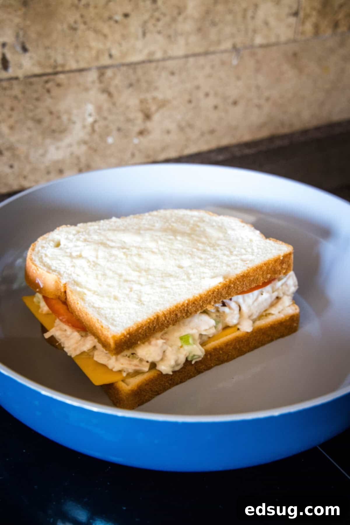 A tuna melt sandwich toasting in a hot skillet, showing the bread turning golden brown and the cheese beginning to melt enticingly.