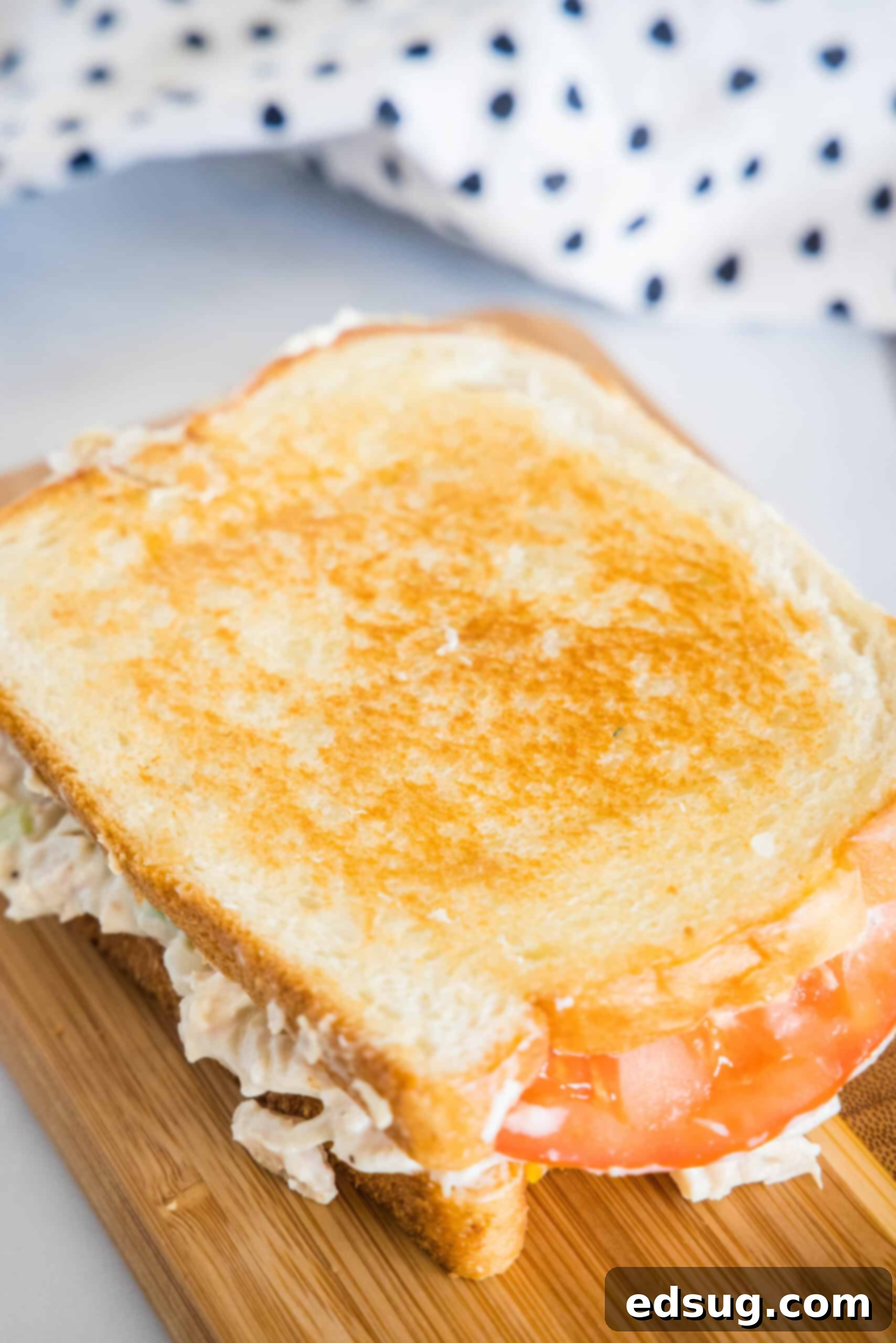 An overhead shot of a freshly grilled tuna melt, sliced in half, resting on a wooden platter, ready to be enjoyed.