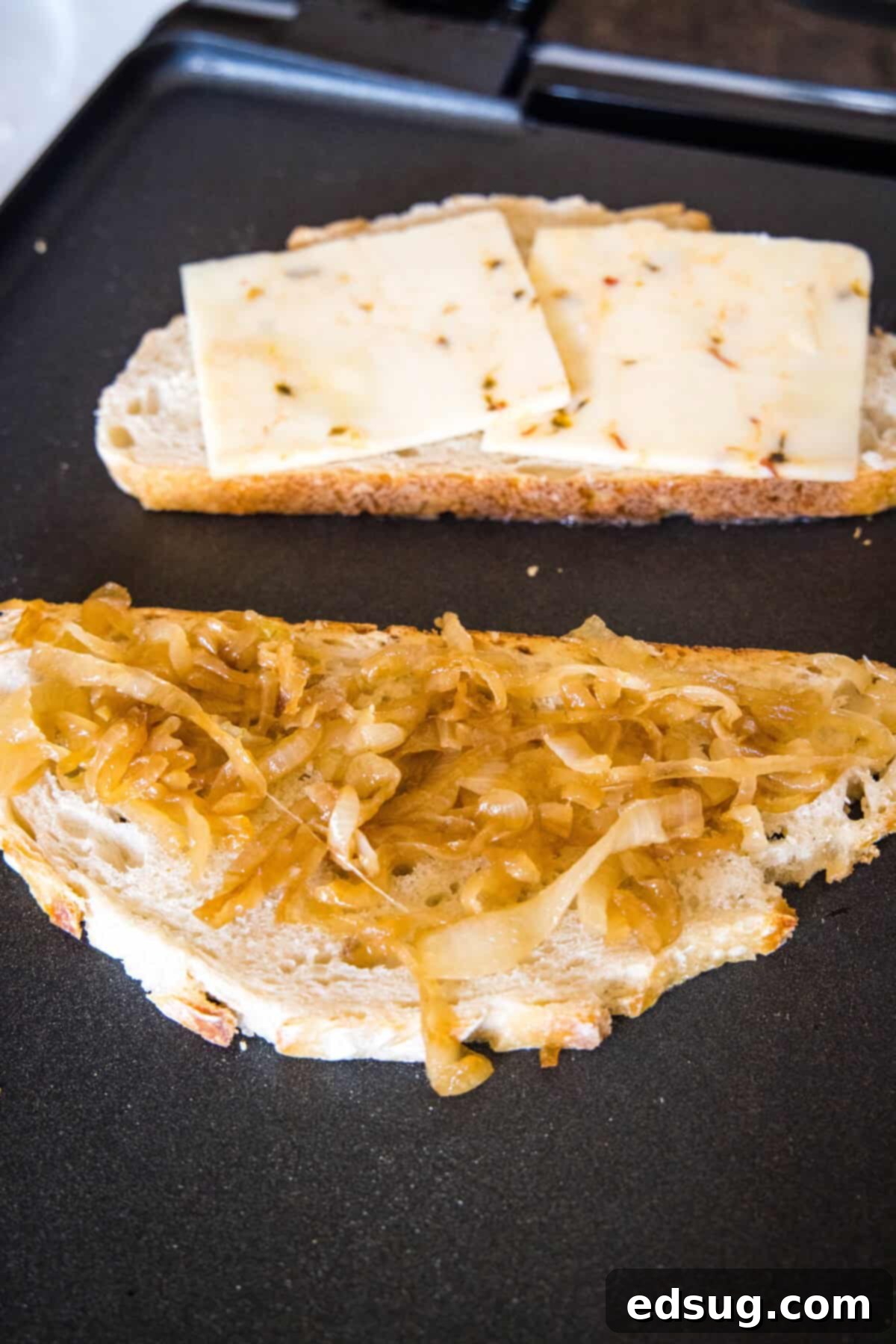 A slice of buttered bread topped with sweet caramelized onions next to another slice ready for cheese and aioli.