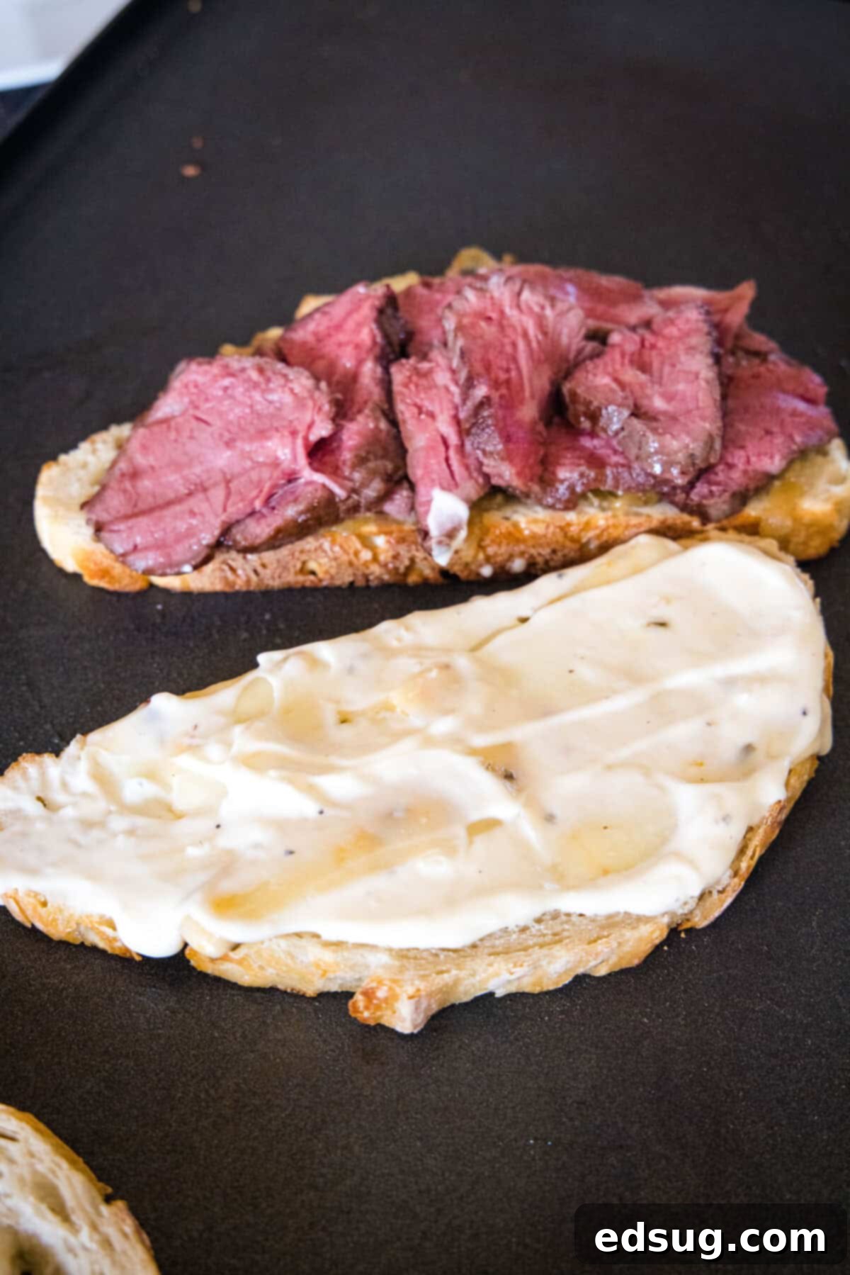 Juicy steak slices are added to one side of the sandwich, while garlic aioli is spread on the melted cheese of the other.