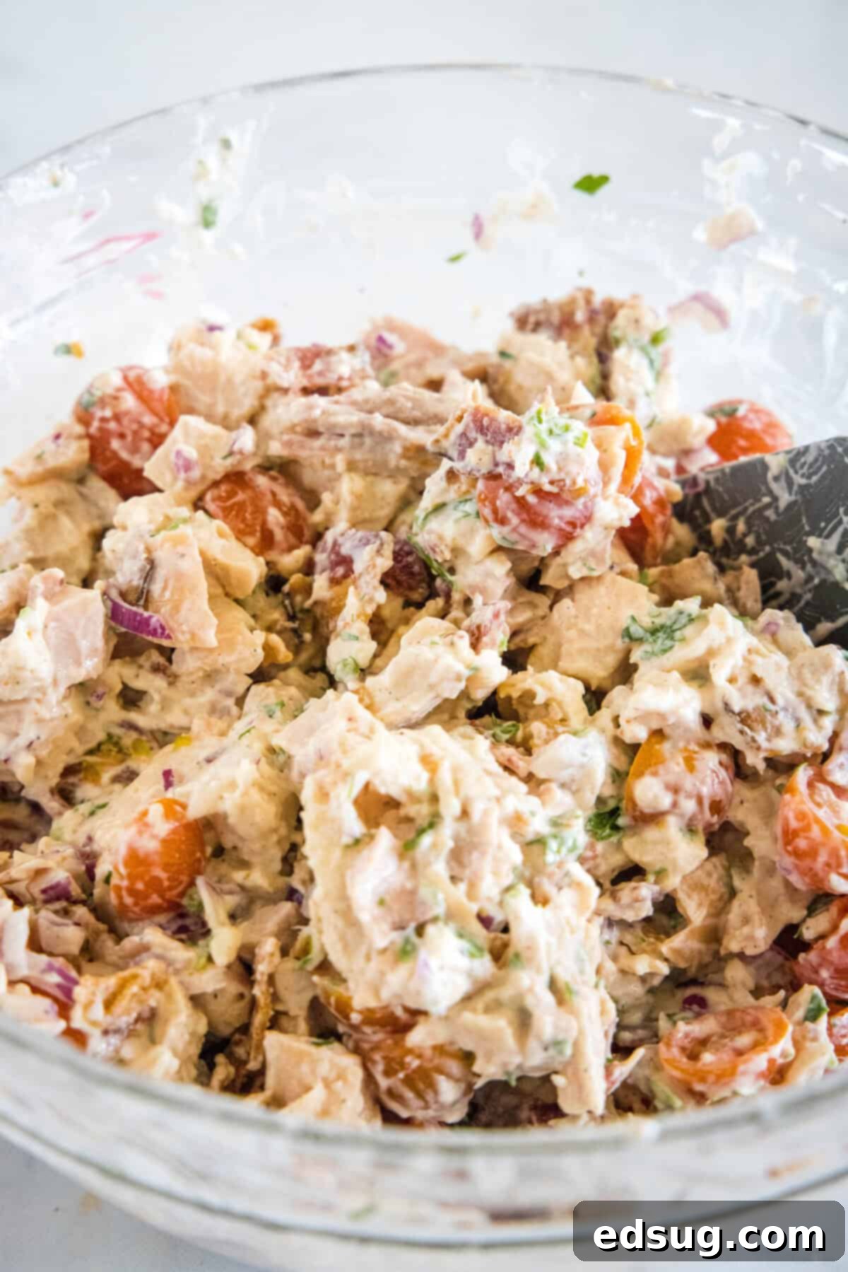 This BLT chicken salad is loaded with juicy shredded chicken, bacon, cherry tomatoes, and crispy red onion tossed with creamy mayo dressing. BLT chicken salad mixed in a glass bowl.