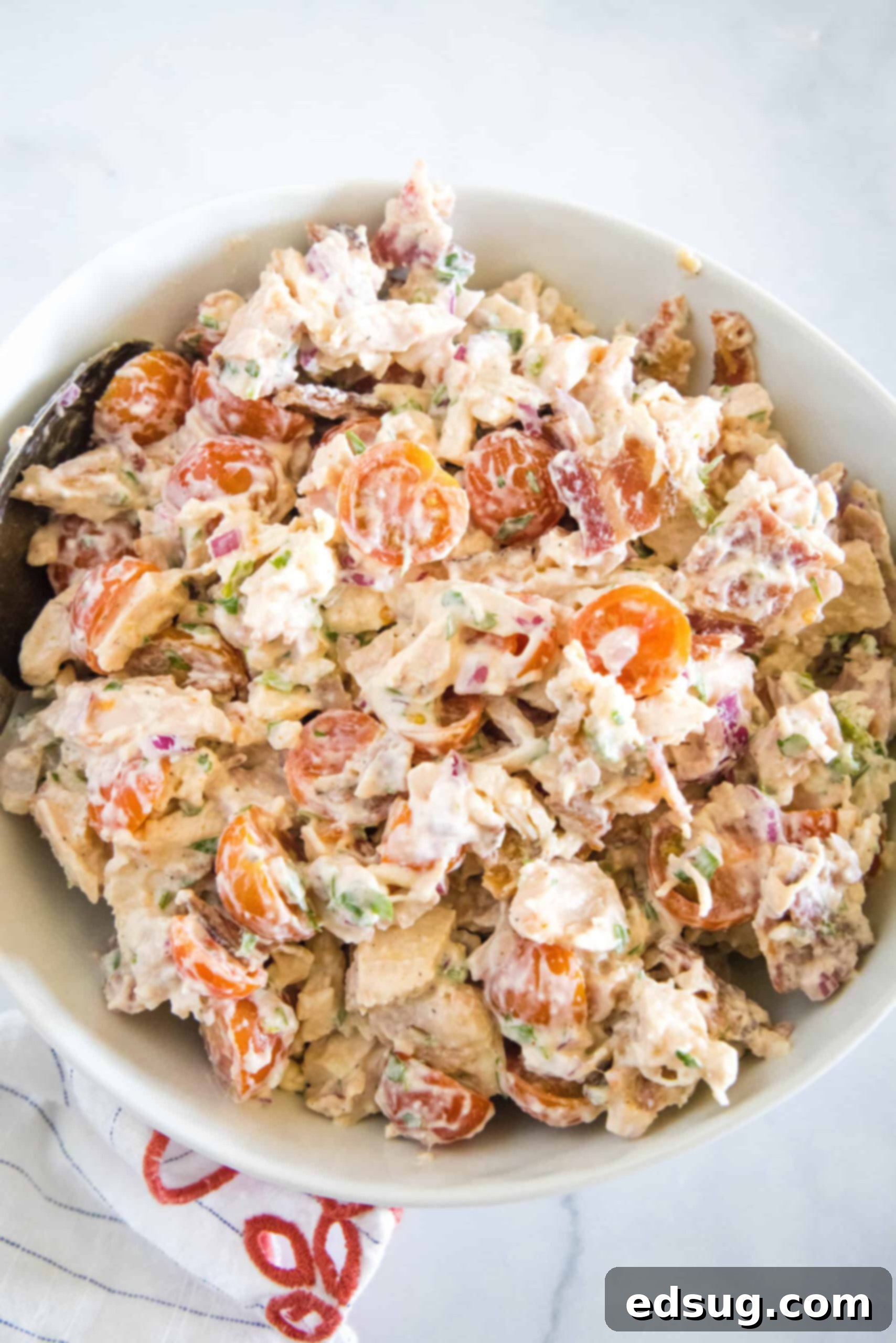 This BLT chicken salad is loaded with juicy shredded chicken, bacon, cherry tomatoes, and crispy red onion tossed with creamy mayo dressing. Overhead view of BLT chicken salad in a white bowl.