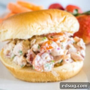 Homestyle BLT Chicken Salad 2 A BLT chicken salad sandwich on a fluffy bun on a white plate.