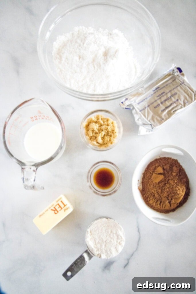 Various ingredients for brownie batter dip laid out on a surface, including cream cheese, butter, sugars, cocoa, and chocolate chips, ready for mixing.